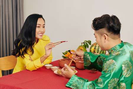 Romantic young couple having tasty food when celebrating Lunar New Year at homeの写真素材