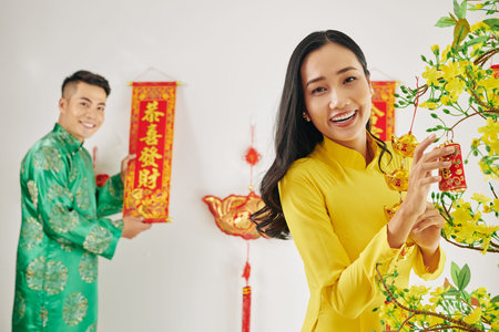 Beautiful happy young couple decorating apartment for Lunar New Year celebrationの写真素材