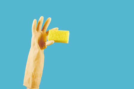Housewife in yellow rubber glove holding kitchen soap , isolated on blueの写真素材
