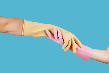 People in rubber gloves holding hands against blue background, helping hand conceptの写真素材