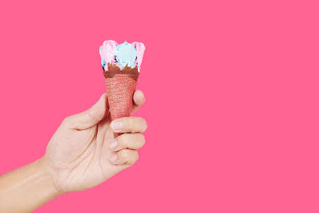Hand holding delicious pink and blue ice-cream in waffle cornの写真素材