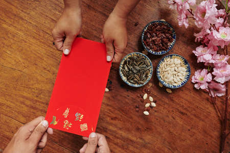 Hands of people exchanging traditional lucky money envelopes on Lunar New Year celebrationの写真素材