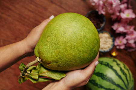 Pomelo fruit in hands of person serving food for Lunar New Year party at homeの写真素材