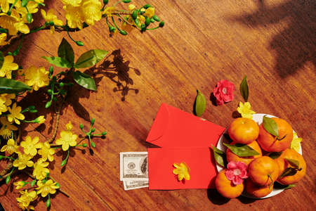 Branches of blooming apricot tree, fruits and red envelopes with money repared for Lunar New Yearの写真素材