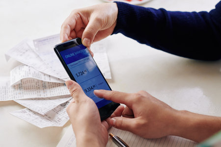 Hands of family members checking expenses via banking mobile application on smartphone