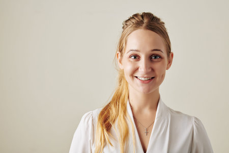 Horizontal medium close up studio portrait of beautiful young woman with blond hair smilng on camera