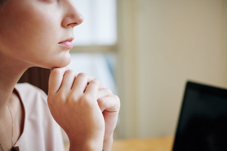 Horizontal close up lower face part shot of attractive young woman resting her chin on hands...