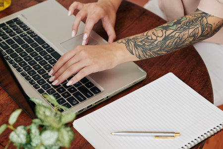 High angle shot of modern young womans hands typing something on laptop