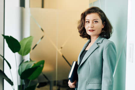 Horizontal medium portrait of attractive mature woman wearing stylish office outfit looking at cameraの写真素材