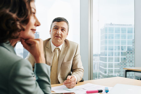 Mature Caucasian businessman and businesswoman working together at office desk, horizontal shot