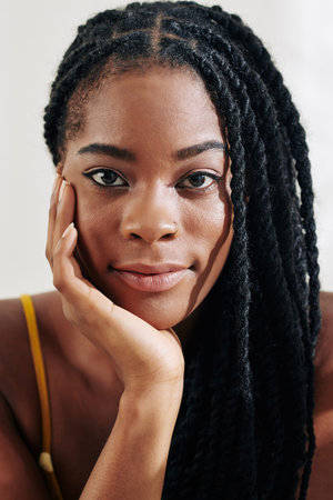 Portrait of young beautiful Black woman with braided hair looking at camera