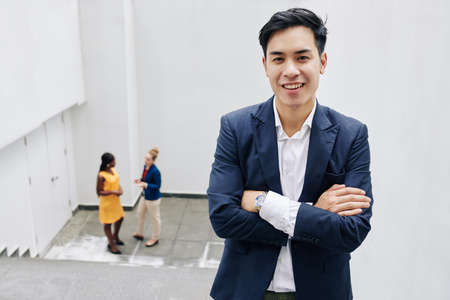 Portrait of young handsome Asian entrepreneur folding arms and looking at cameraの写真素材