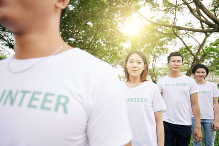 Group of positive volunteers walking in park they are cleaning from garbadgeの写真素材