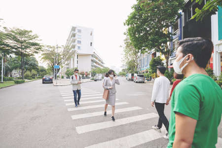 Asian people in protective maskes crossing road in quarantined city during coronavirus epidemicの写真素材