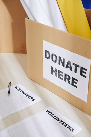 Donation cardboard box with empty lists of volunteers on table