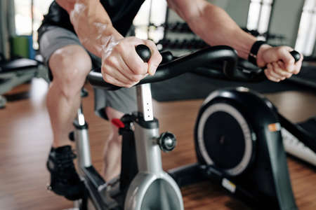 Cropped image of sportsman riding stationary bike in gym before working outの写真素材