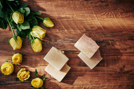 Handmade organic soap bars and rose flowers on wooden table, view from aboveの写真素材