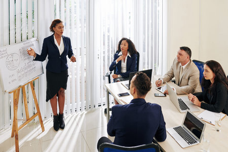 Pretty young businesswoman showing sales report and suggesting new way of company development
