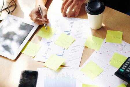 Startupper analyzing financial chart and writing new ideas and plans on yellow stickers