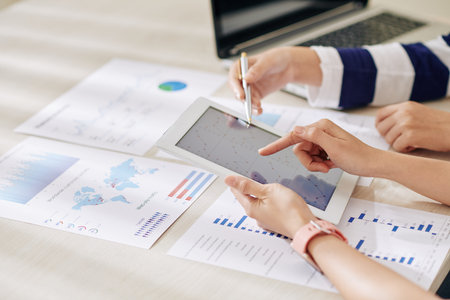 Female financial analysts discussing information on digital tablet when working on annual report