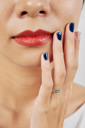 Cropped image of woman with manicured nails touching her faceの写真素材