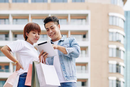 Happy young Vietnamese couple using application on tablet computer when shopping onlineの写真素材