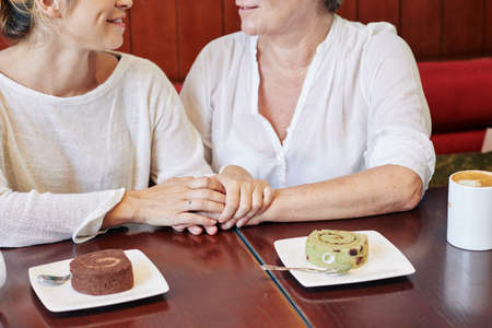 Cropped image of mother and daughter eating tasty desserts, sharing secrets and supporting each otherの写真素材