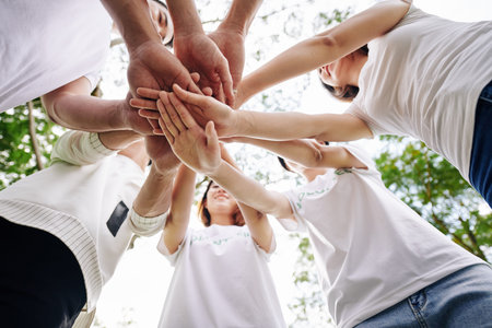 Team of student volunteers stacking hands to show support and unity before starting cleaning college...