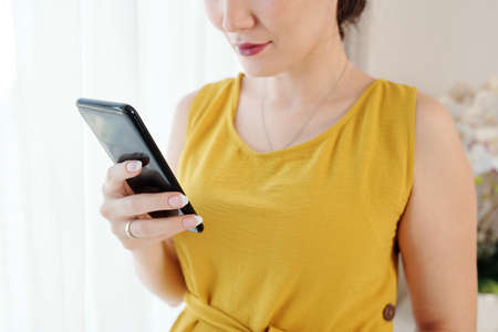 Close-up image of woman checking messages and notifications on smartphoneの写真素材