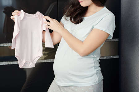 Pregnant young woman holding light pink cotton body for her babyの写真素材