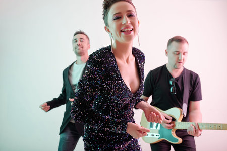 Cheerful beautiful female singer snapping fingers when performing with her bandの写真素材