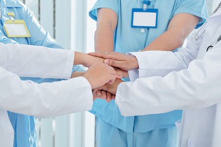 Group of medical worker stacking hands to express unity before long day at work during epidemic periodの写真素材