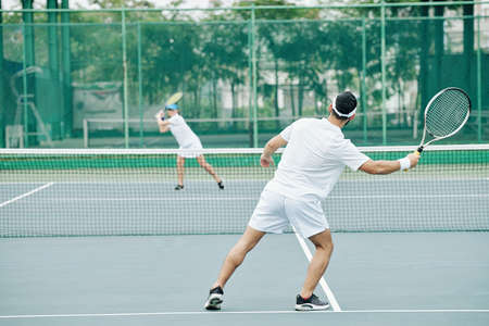 Couple in white uniform having tennis match on courtの写真素材