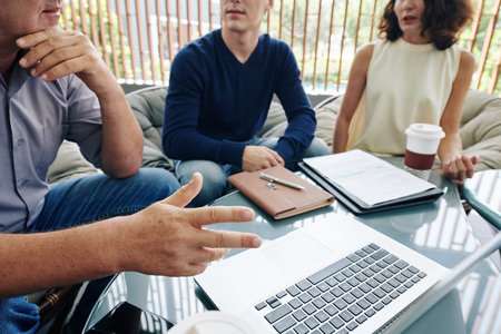 Cropped image of business people arguing at meeting in cafe when watching presentation on laptop