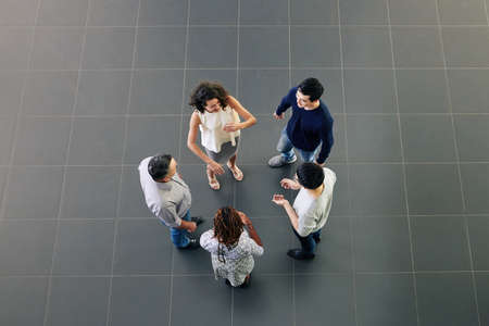 Group of cheerful multi-ethnic business people discussing news, gossips and ideas during break, view from aboveの写真素材