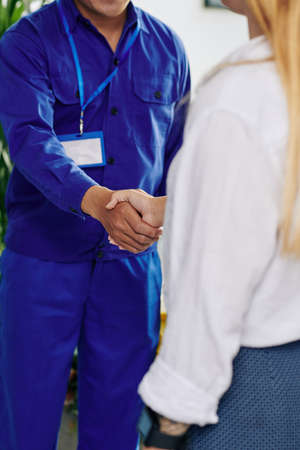 Close-up image of female customer shaking hand of plumber entering her apartmentの写真素材