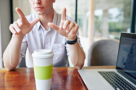 Cropped image of businessman drinking take out coffee when showing presentation on new product to colleague at meetingの写真素材