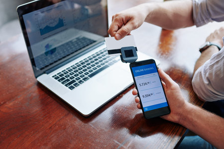 Businessman swiping credit card through reader attachend to smartphone when using online banking...