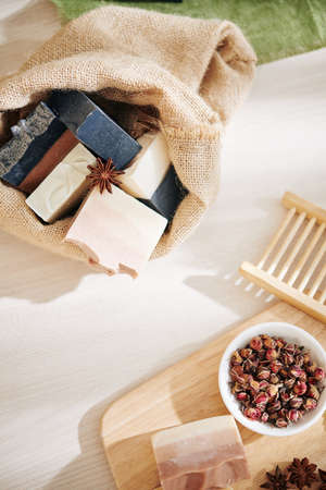 Sack of scented soaps and bowl with dry rose buds on table with workshop, view from aboveの写真素材