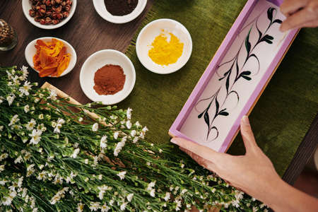 Hands of woman holding mold with handmade soap mixture with beautiful swirlsの写真素材
