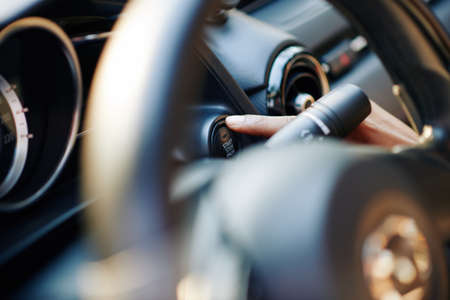 Close-up image of female driver pushing launch control button in modern carの写真素材