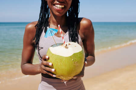 Happy young woman enjoying refreshing coconut cocktail after joggingの写真素材