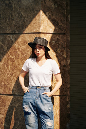 Portrait of young attractive Asian woman posing in jeans, white t-shirt and straw hat