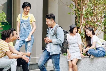 Cheerful Vietnamese university students spending break on university campusの写真素材