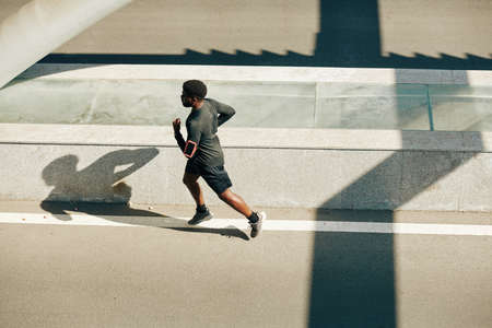 Young fit Black man running outdoors in the morningの写真素材