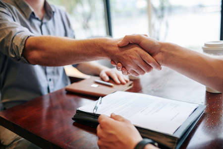 Close-up image of business people shaking hands after signing contractの写真素材