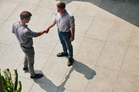 Young confident business people standing outdoors and shaking hands after meetingの写真素材