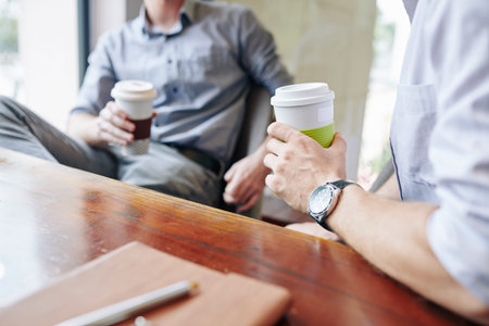 Business people drinking coffee and discussing news during short break in office