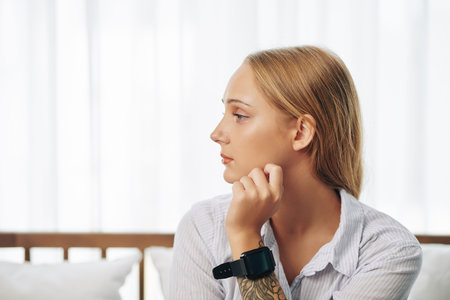 Pensive pretty young woman with smartwatch on her wrist looking away