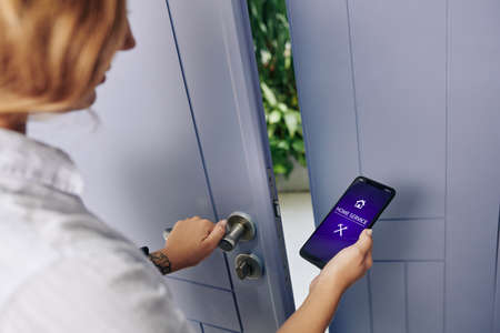 Young woman using home service application to call handyman as her entrance door lock is brokenの写真素材